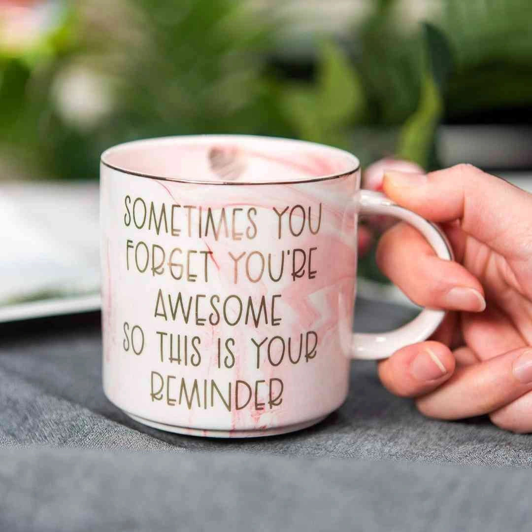 Person holding a pink marble coffee mug with the quote "Sometimes You Forget You’re Awesome" printed in gold