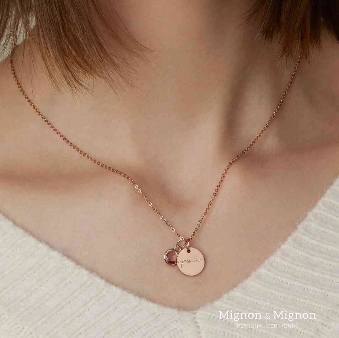 Rose gold necklace with custom name disc and birthstone charm, worn around the neck